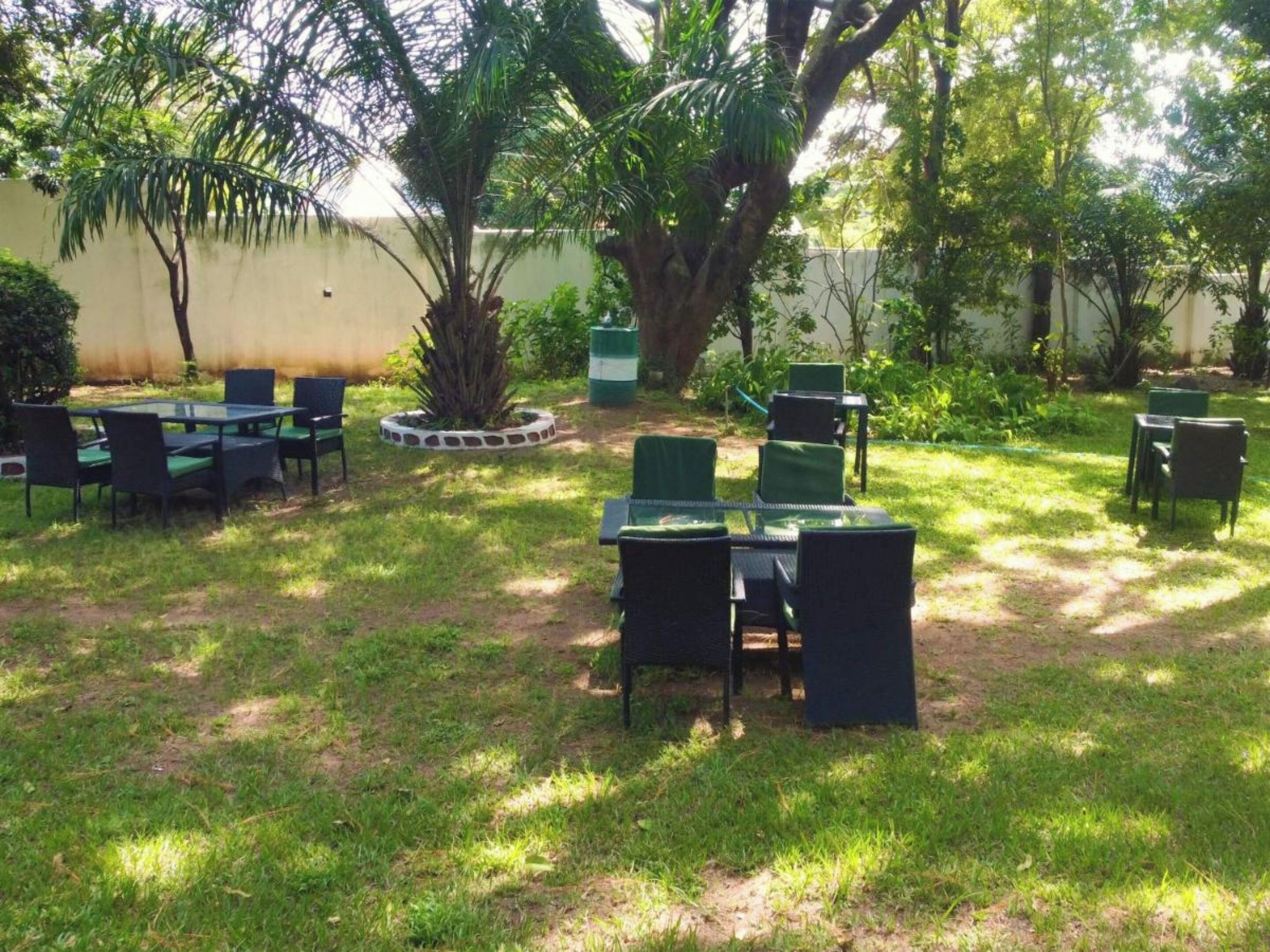 An outdoor seating area with tables and chairs, surrounded by greenery and trees.