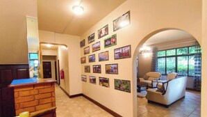 Een ruime lobby met betegelde vloer, een receptiebalie, een muur versierd met ingelijste foto's, en een zithoek met uitzicht door grote ramen.