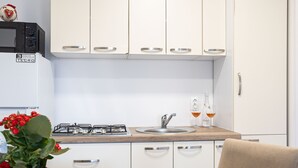 Eine moderne Küche mit weißen Schränken, einem Gasherd, einer Spüle und einem Essbereich mit Tisch und Stuhl.