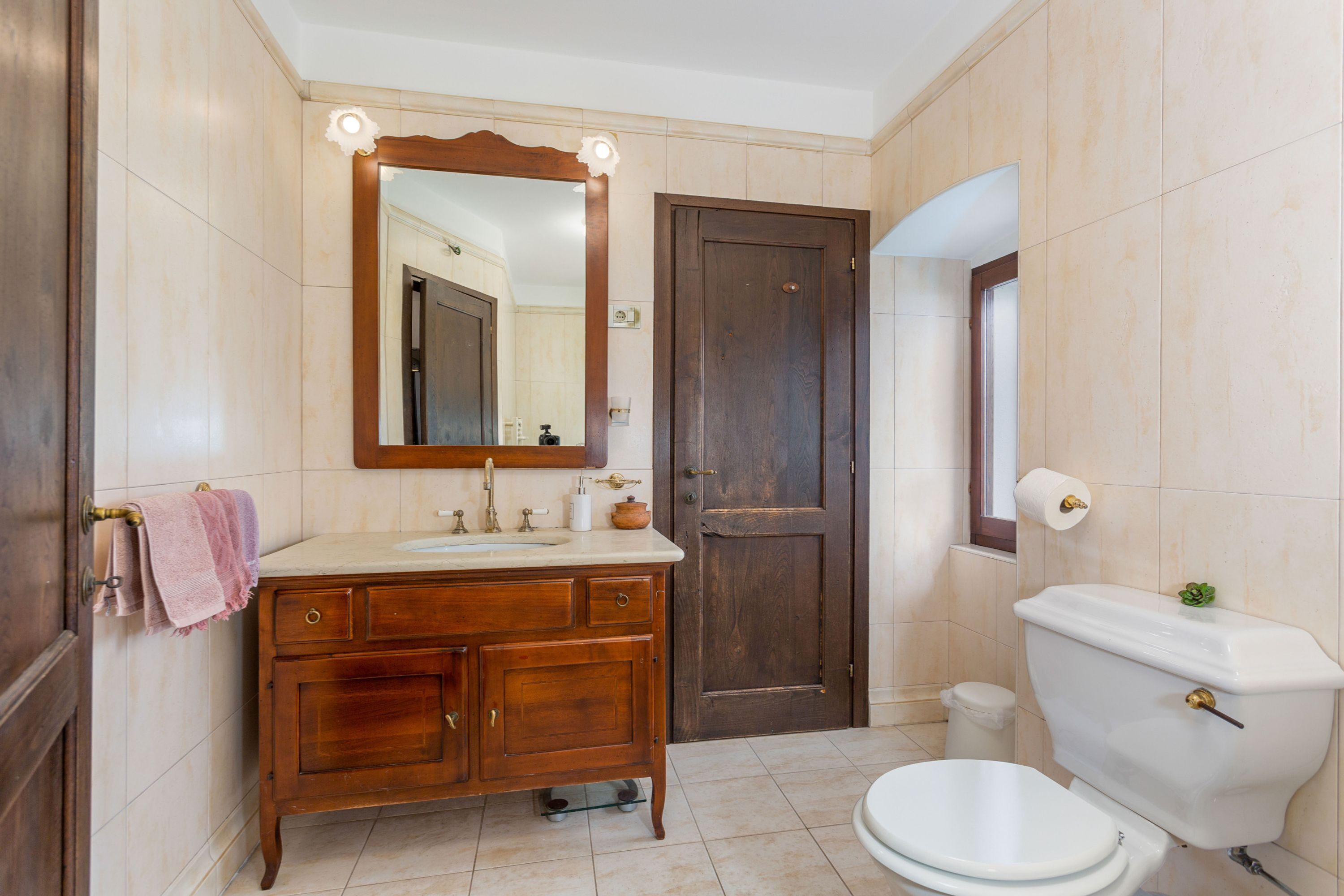 Ein Badezimmer mit einem Holzbadezimmerwaschbecken, einem großen Spiegel, einer Toilette und einem Waschbecken.
