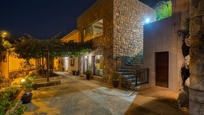A stone building with a staircase, potted plants, and a well-lit entrance. - Villa Karla in Poljane (Opatija)