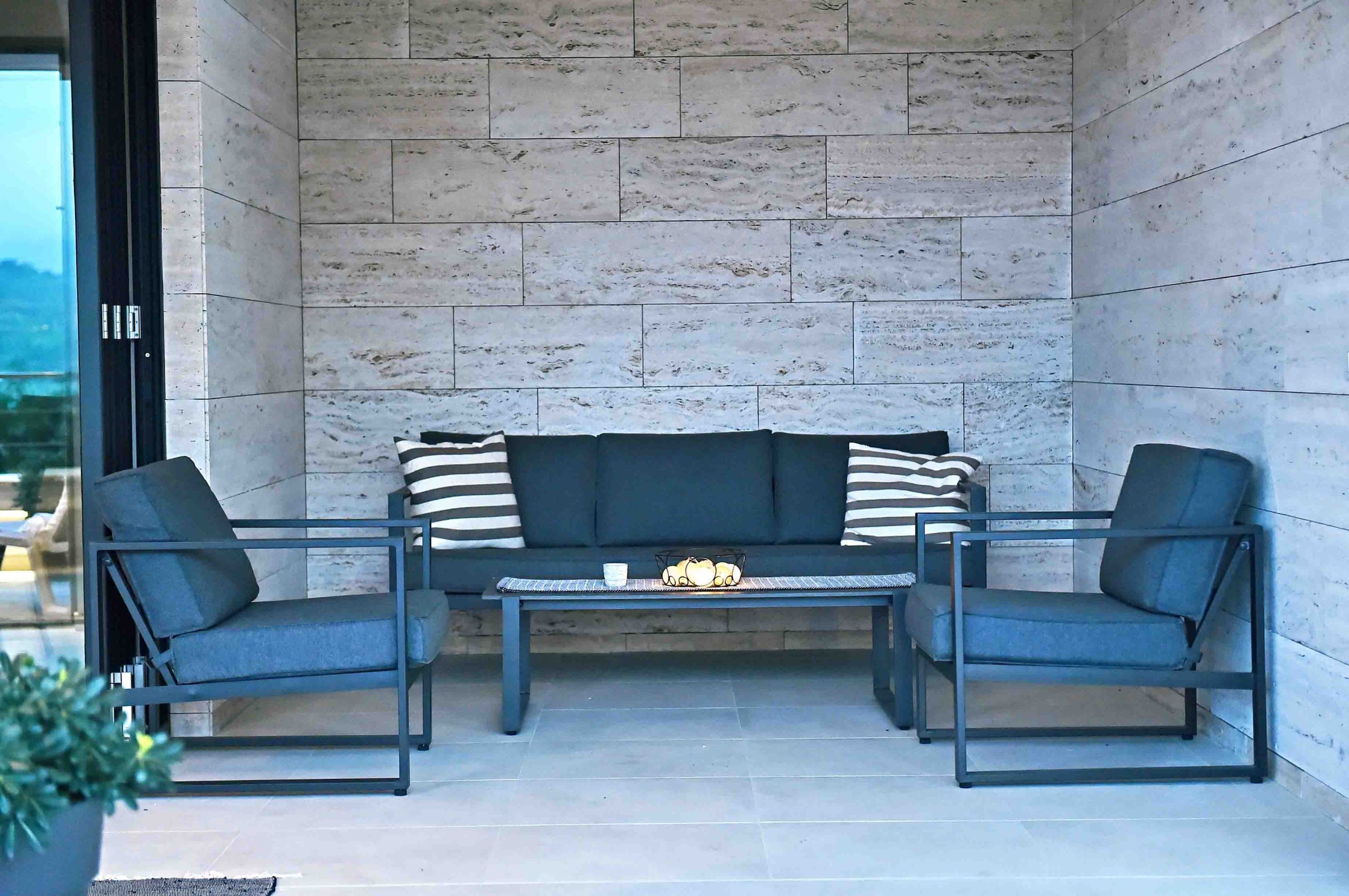 Un espace de détente extérieur moderne, comprenant un canapé et deux fauteuils, une petite table et un objet décoratif.