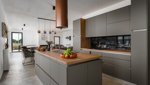 Een moderne keuken met grijze kastjes, een houten aanrechtblad en een groot eiland met een fruitschaal.