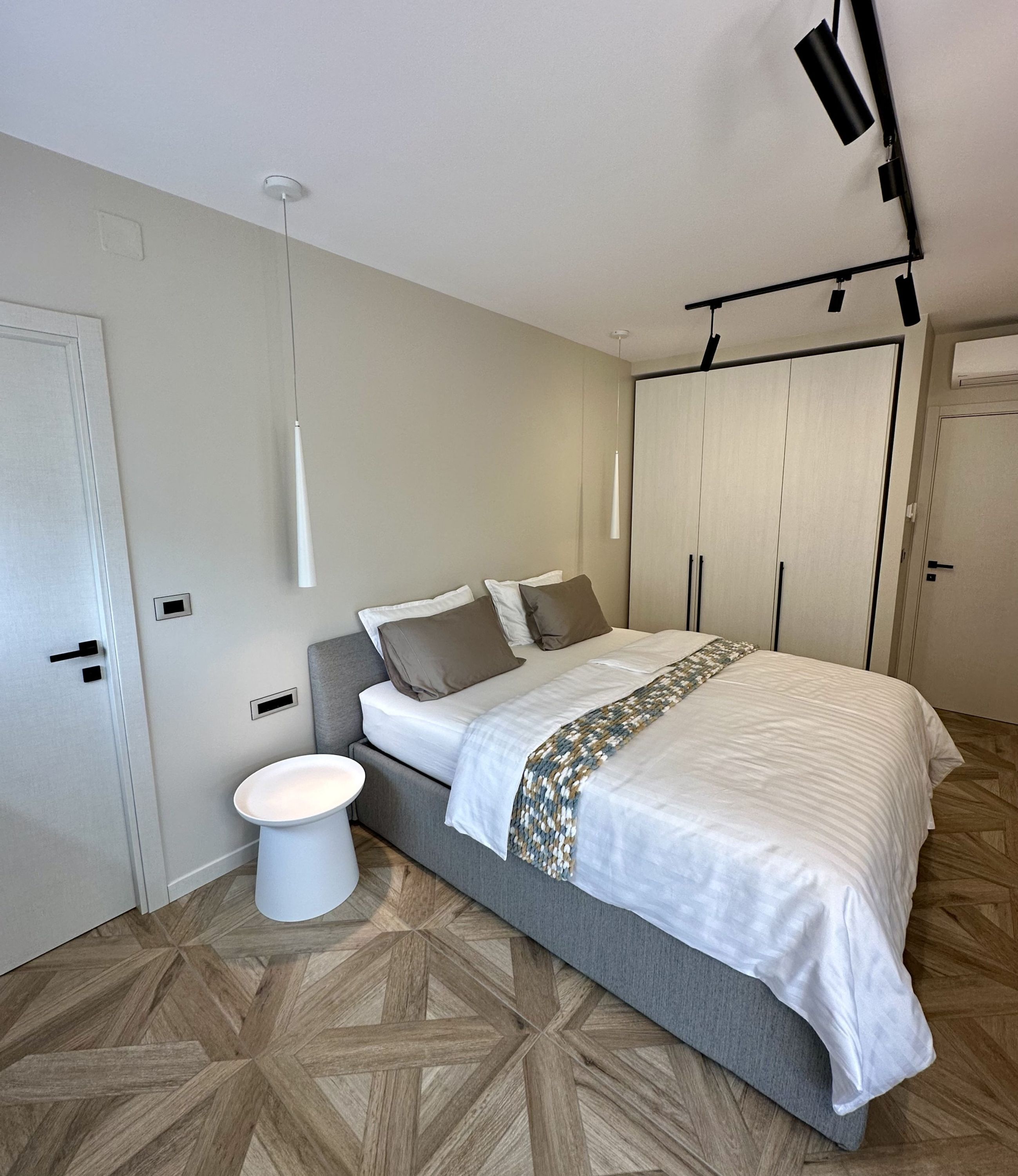 A modern bedroom with a bed, bedside table, and a wardrobe.