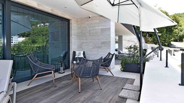 Eine moderne Terrassengrundstück mit Korbmöbeln, einem großen Sonnenschirm und Blick auf die Umgebung.