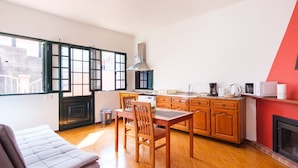 A compact kitchen with wooden cabinets, a dining table, and a sofa. - GuestReady - Serene Paradise in Machico (Machico)