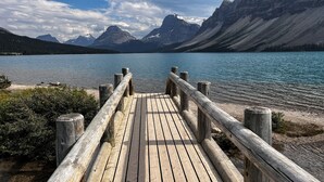 Un muelle de madera que conduce a un lago tranquilo con montañas al fondo.
