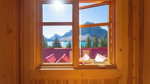 Una ventana con marco de madera que ofrece una vista despejada de un paisaje montañoso y un lago.