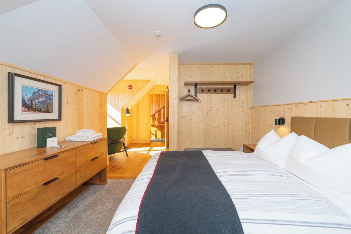 Una habitación de hotel con cama, cómoda de madera y un cuadro en la pared.
