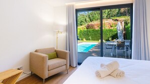 Habitación de hotel con cama, una silla, una lámpara y vistas a una piscina exterior y zona de patio.