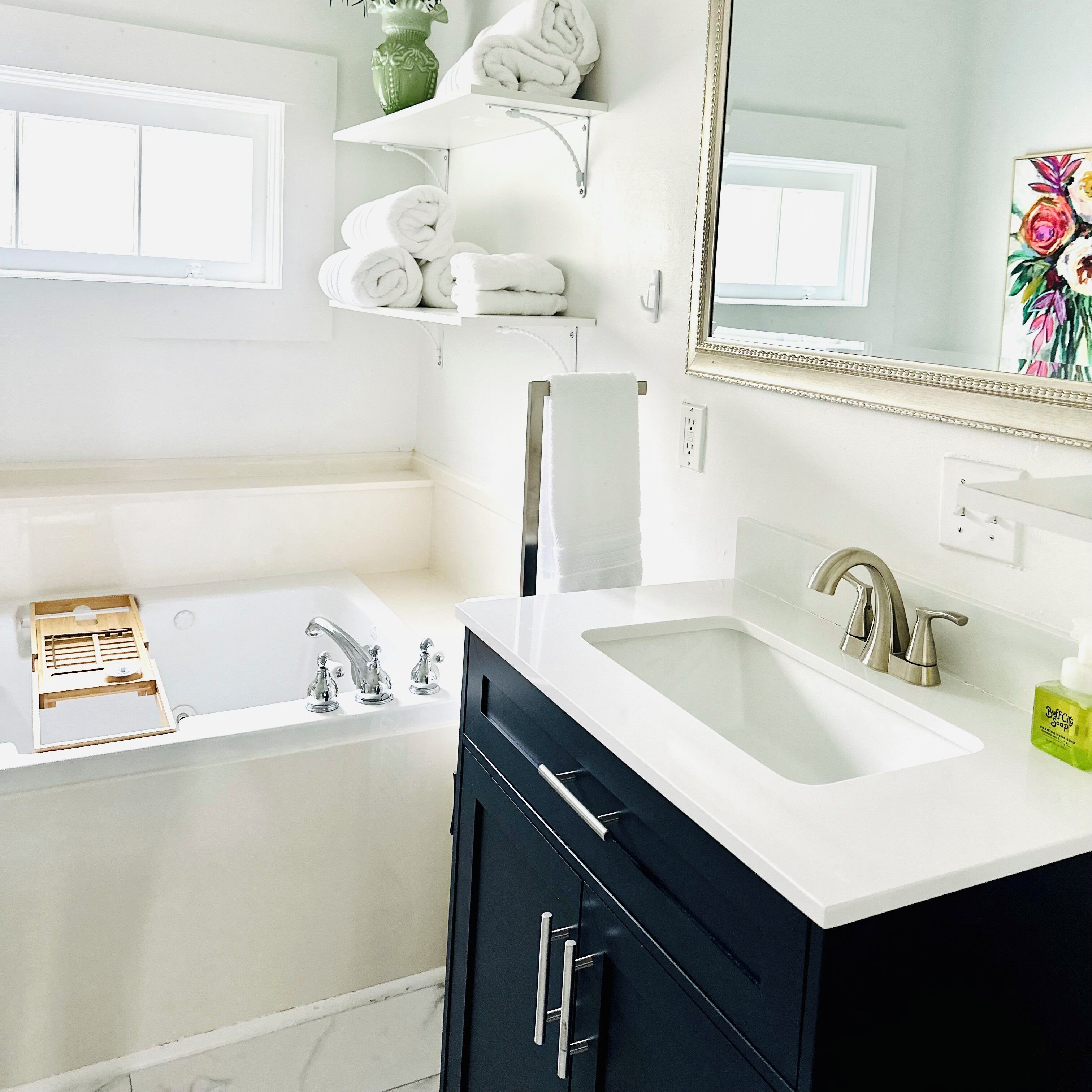 A modern bathroom with a bathtub, two sinks, and a vanity with cabinets.