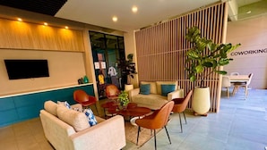 A modern living area with a sofa, chairs, a coffee table, and a TV. - Bright Studio with Balcony 615 (Bogotá)