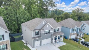 A two-story residential house with a garage, a covered porch, and a well-maintained lawn. - Luxury 5BR Ideal For Vacationers, Groups, Corporate & Insurance Stays Near ATL (Fairburn)