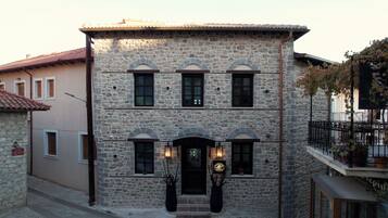 A stone building with a central entrance, multiple windows, and a balcony with potted plants.