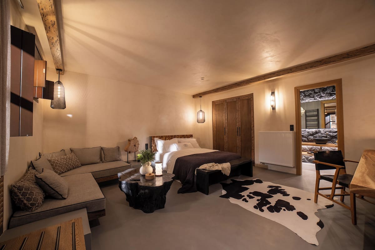 Une chambre confortable avec un lit, un canapé, une table basse et un tapis en peau de vache.