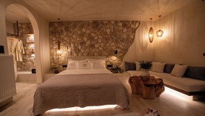 Ein Schlafzimmer mit einer Steinsturz, einem großen Bett, einem Holznachttisch und einem Sofa.