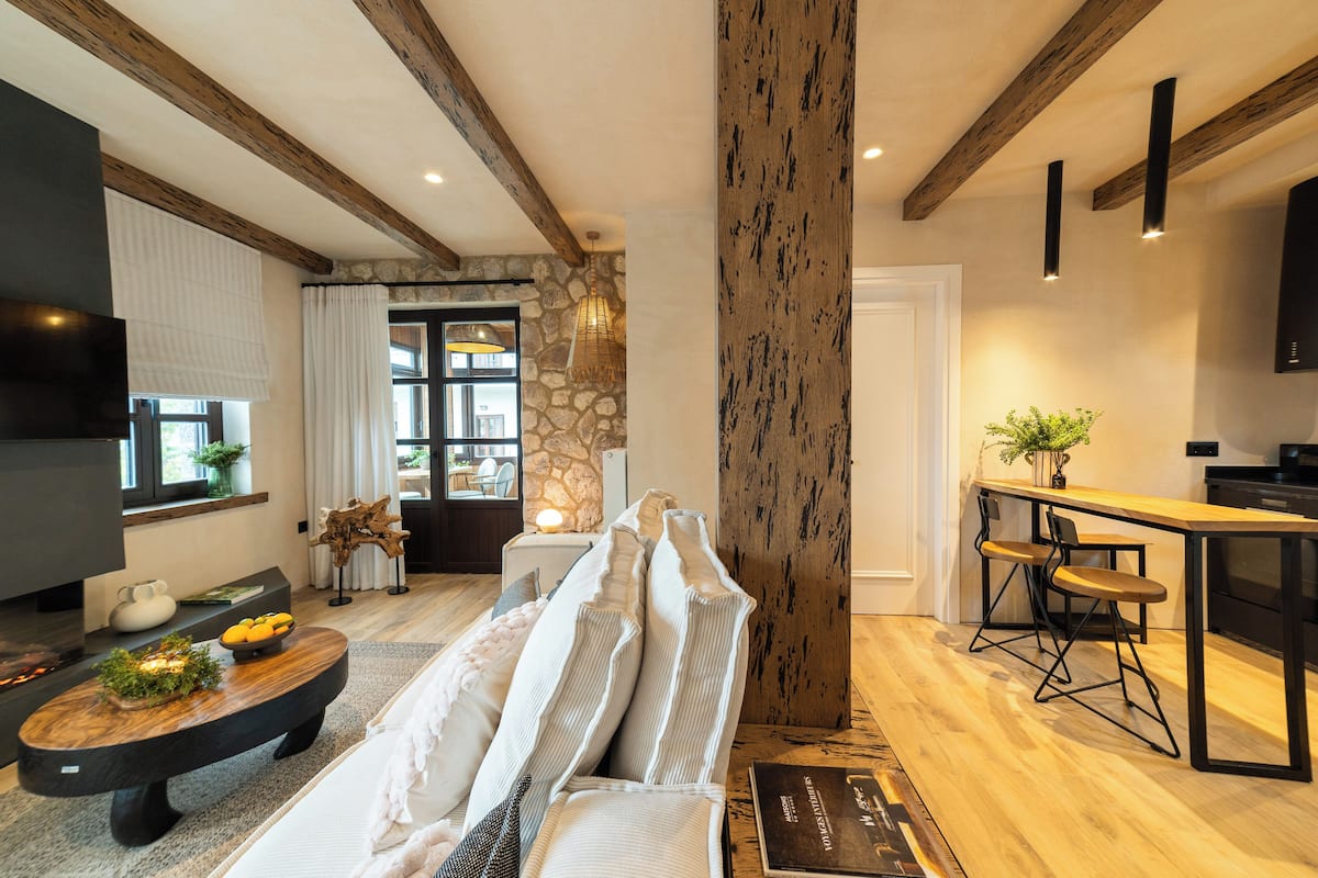 Un salon moderne avec un canapé, une table basse et un coin cuisine comprenant un bar et des tabourets.