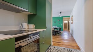 A compact kitchen with a modern stove, kettle, and a dining area with a table and chairs. - Authentic Parisian Elegance in the Heart of the 6th Arrondissement (Paris)