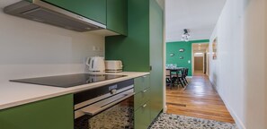 Una cocina compacta con estufa moderna, hervidor y comedor con mesa y sillas.