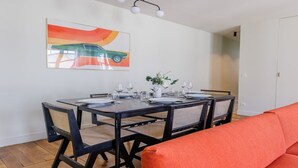 A dining area with a table set for four, chairs, and a painting on the wall. - Authentic Parisian Elegance in the Heart of the 6th Arrondissement (Paris)