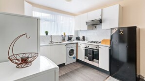 Una cocina moderna con armarios blancos, un refrigerador negro, una lavadora y una estufa.