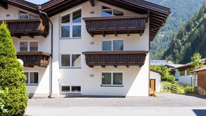 A multi-story building with balconies, a mountain backdrop, and a clear sky.
