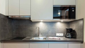 A modern kitchen with a stainless steel sink, a Bosch microwave, and a coffee maker on the countertop.