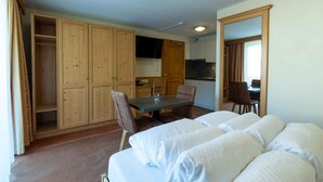 A bedroom with a bed, a dining table, and a kitchen area.