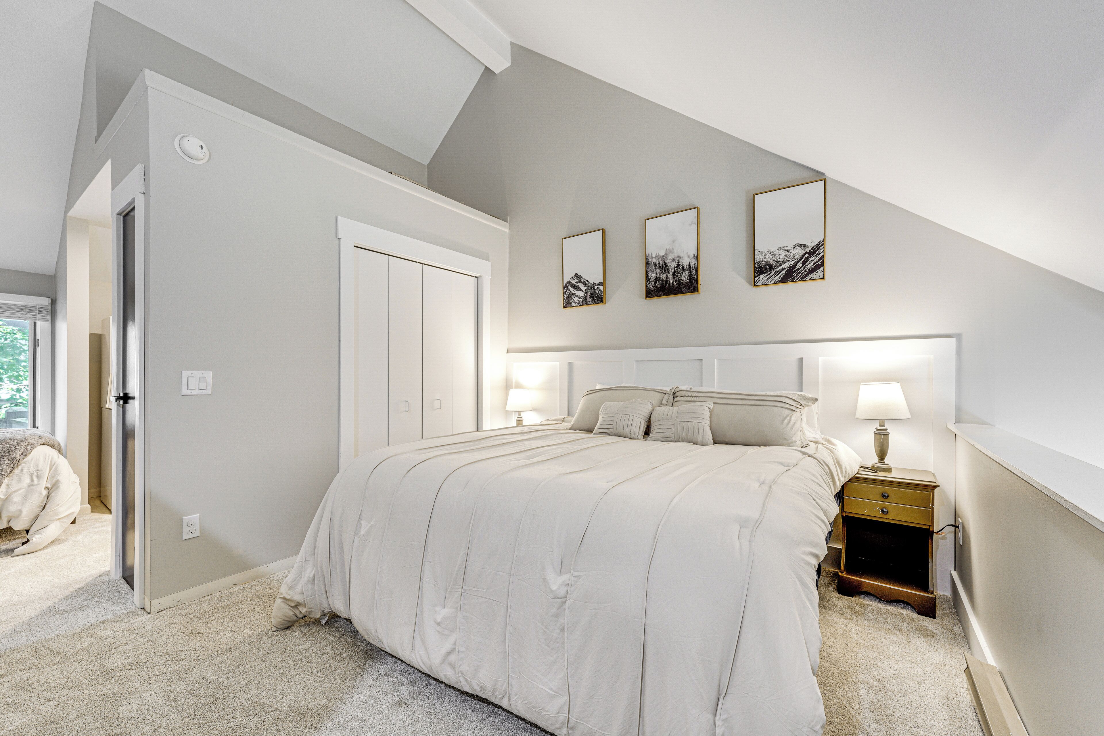 A bedroom with a bed, nightstand, and wall art.