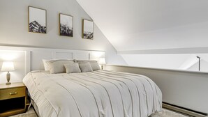 Een slaapkamer met een bed, nachtkastjes en kunst aan de muur.