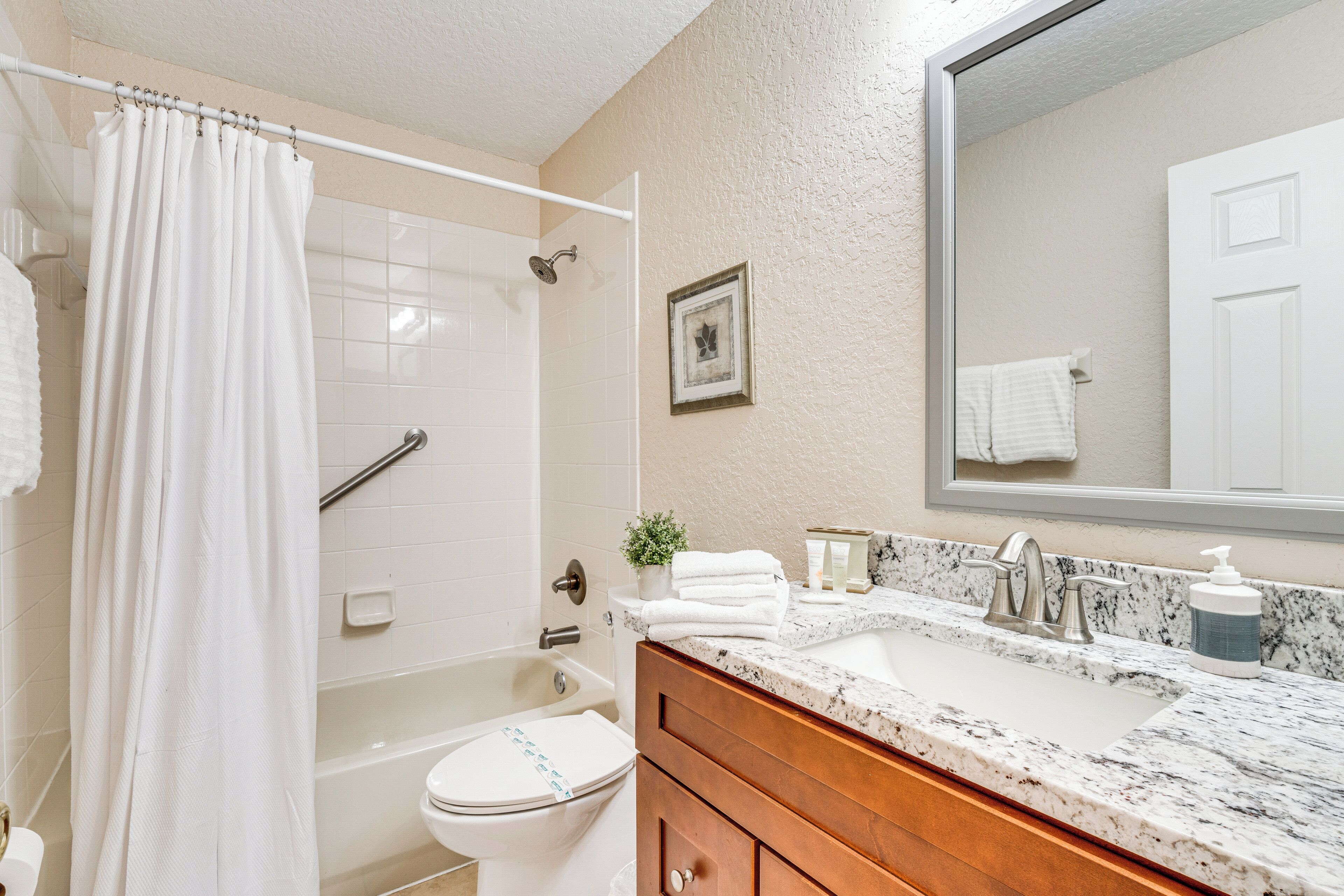 A bathroom with a shower, toilet, sink, and vanity.