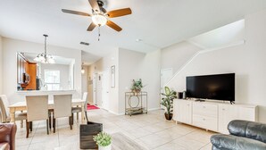 A modern living room with a dining area, a ceiling fan, a flat-screen TV, and a potted plant. - Davenport Retreat w/ Resort Perks, 9 Mi to Disney! (Davenport)