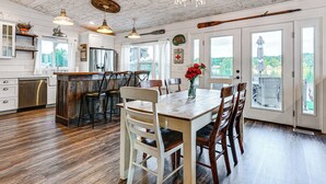 A spacious kitchen with wooden floors, a dining area with a large table and chairs, and a view of a lake through the windows. - Family-friendly Retreat on Gilletts Lake! (Jackson)