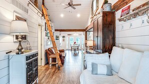 A cozy interior with a wooden floor, a white sofa, a dining area, and a ladder leaning against the wall. - Family-friendly Retreat on Gilletts Lake! (Jackson)