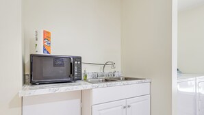 A kitchen with a microwave, a box of detergent, a sink, and a washing machine. - Walkable Mobile Apartment w/ Fenced-in Yard (Mobile)