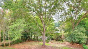A tree-lined yard with a grassy area and a stone pathway. - Walkable Mobile Apartment w/ Fenced-in Yard (Mobile)