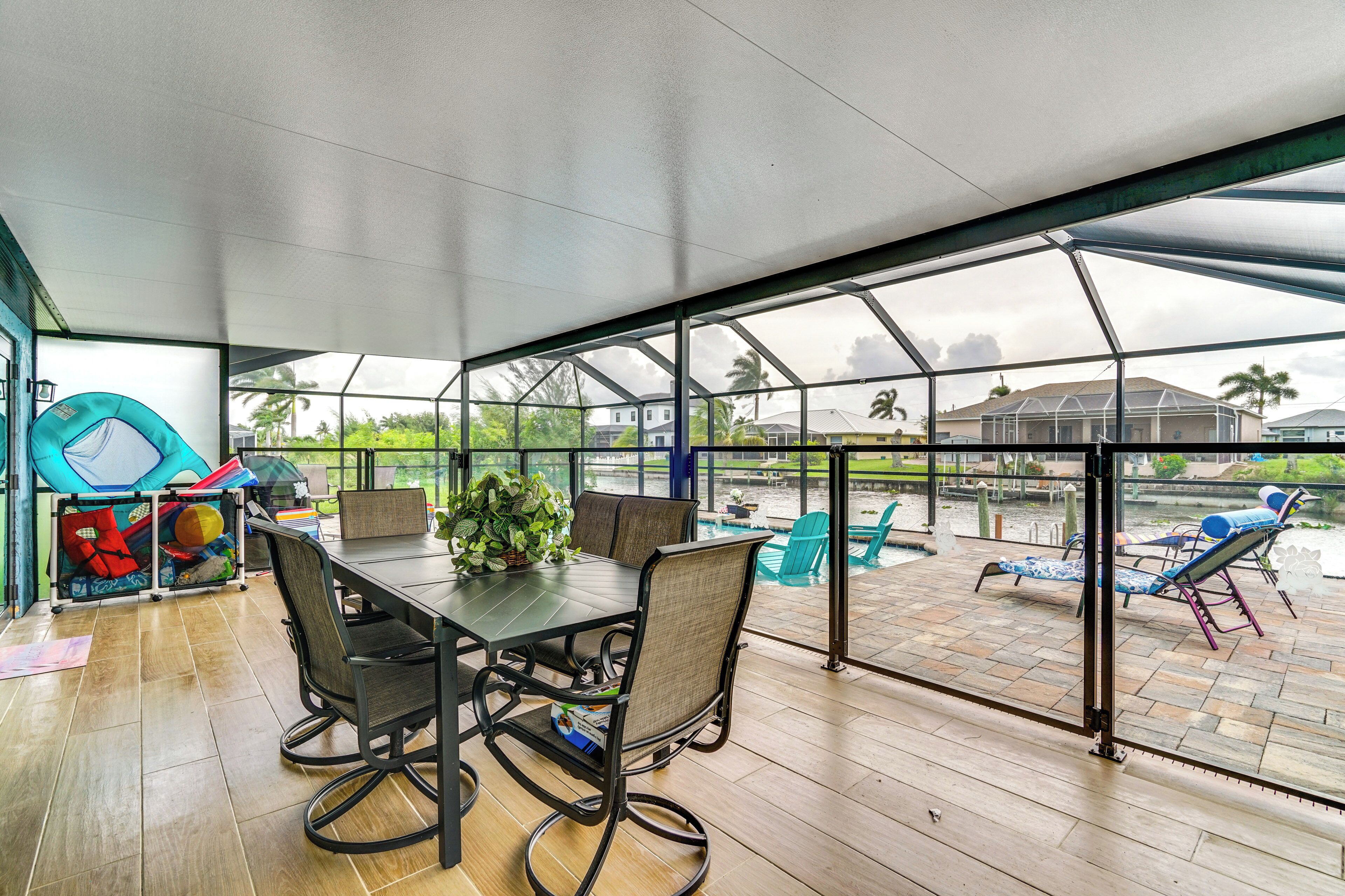 Eine überdachte Terrasse mit Tisch und Stühlen mit Blick auf einen Poolbereich.