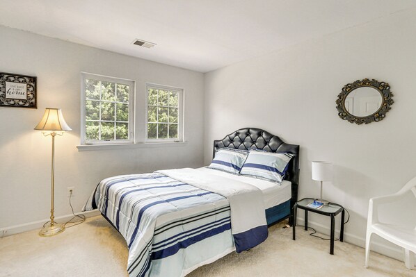 A bedroom with a bed, a nightstand, a chair, a floor lamp, and a window.