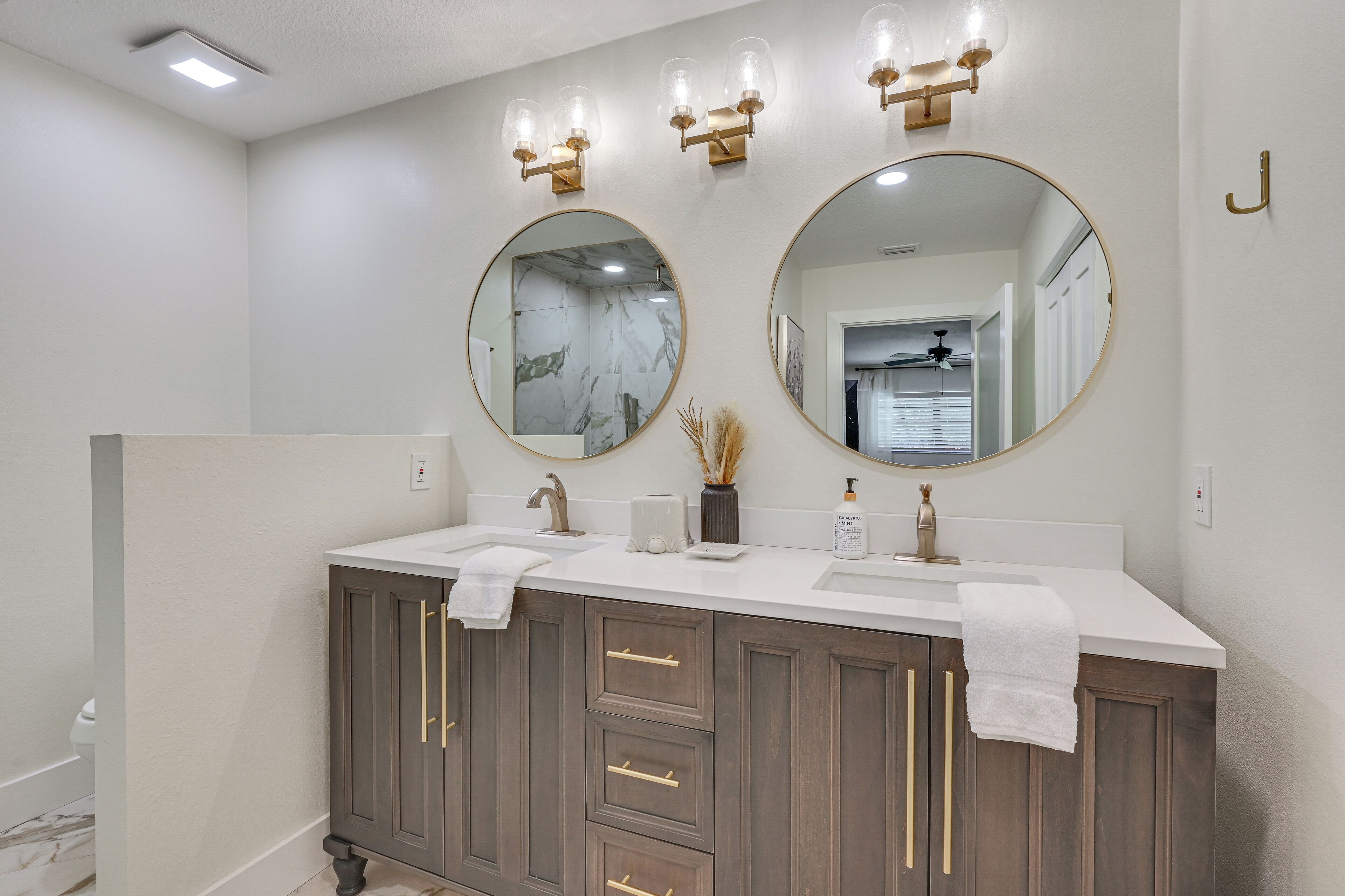 A bathroom with a double sink vanity, two wall-mounted mirrors, and a towel rack.