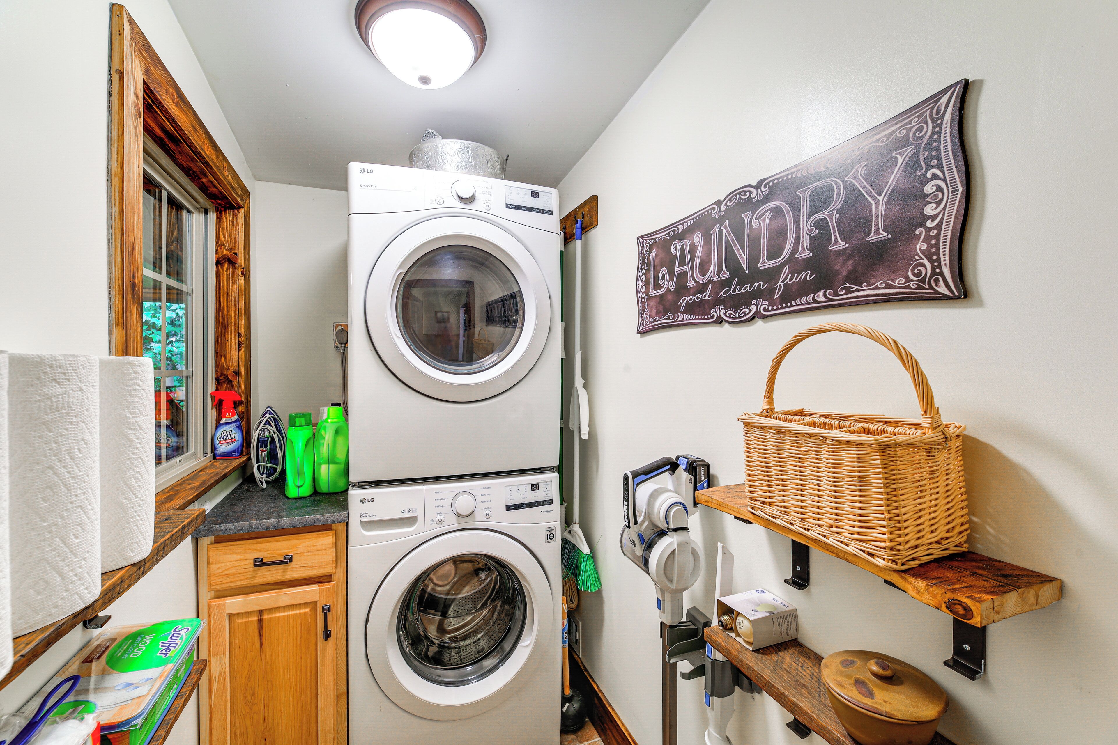 A laundry room with a front-loading washer and dryer, a wicker basket on a shelf, and a sign that says "LAUNDRY good clean fun".