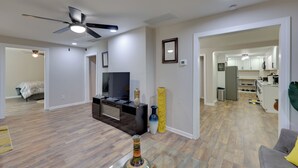 A spacious living room with a ceiling fan, a flat-screen TV, and a decorative vase. - Walkable Greenville Home Near Dtwn (Greenville)