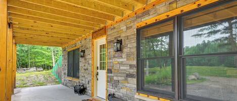 A covered porch with a stone wall and large windows.