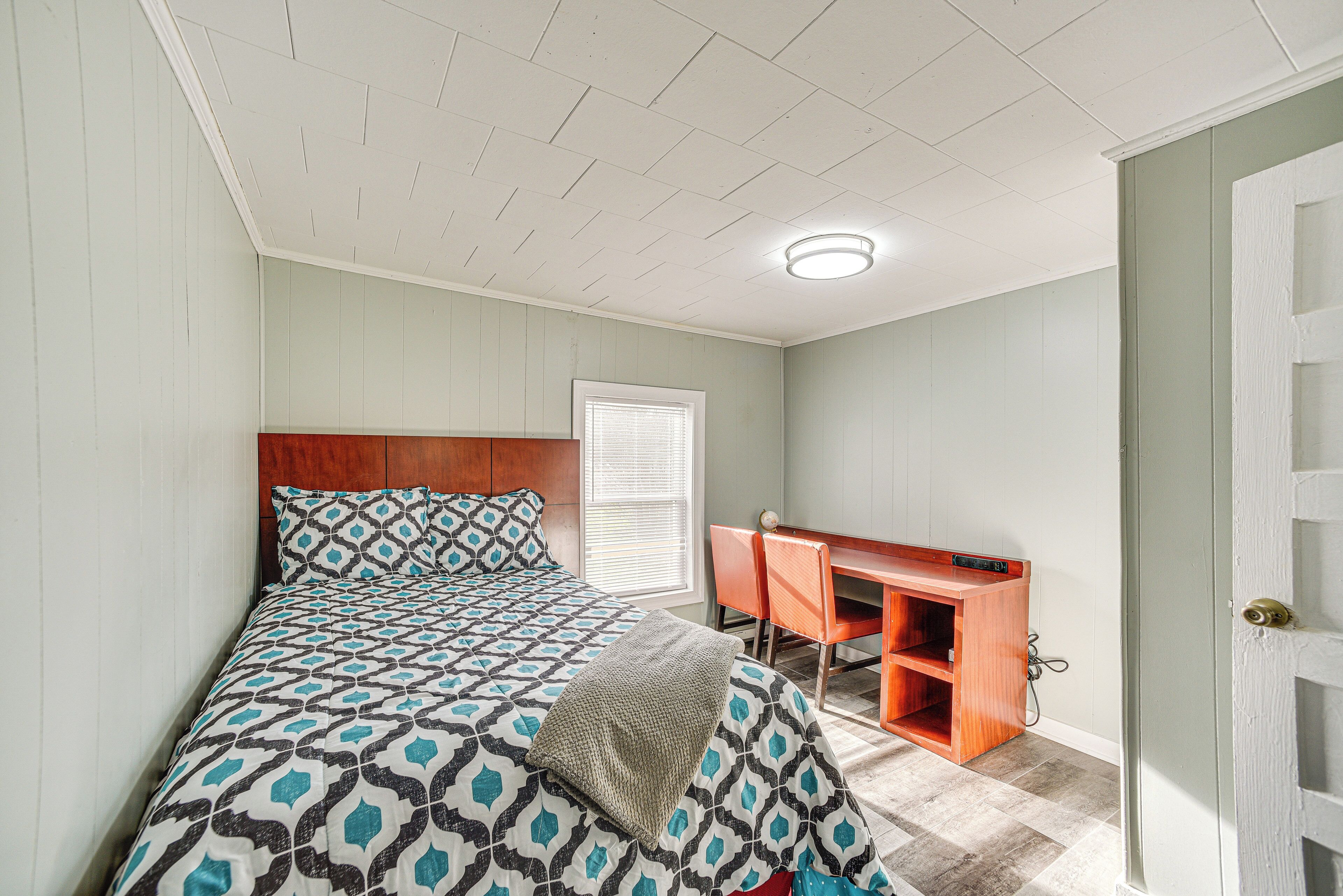 A bedroom with a bed, a desk, and a window.