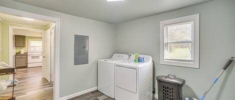 A laundry room with a washing machine, a laundry basket, and a mop.