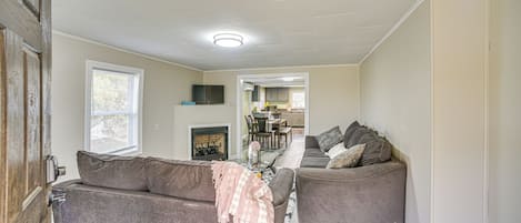 A living room with two grey sofas, a fireplace, and a dining area in the background.