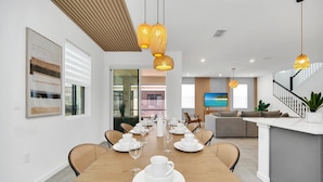 A modern dining area with a wooden table set for a meal, surrounded by wicker chairs.