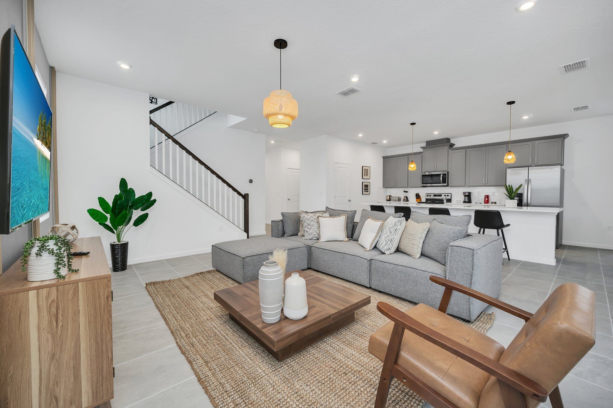 A modern living room with a sectional sofa, a coffee table, and a staircase leading to an upper floor.