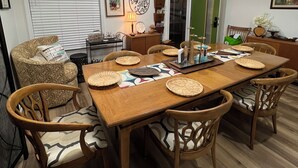 A dining area with a wooden table, six chairs, and a hanging light fixture.