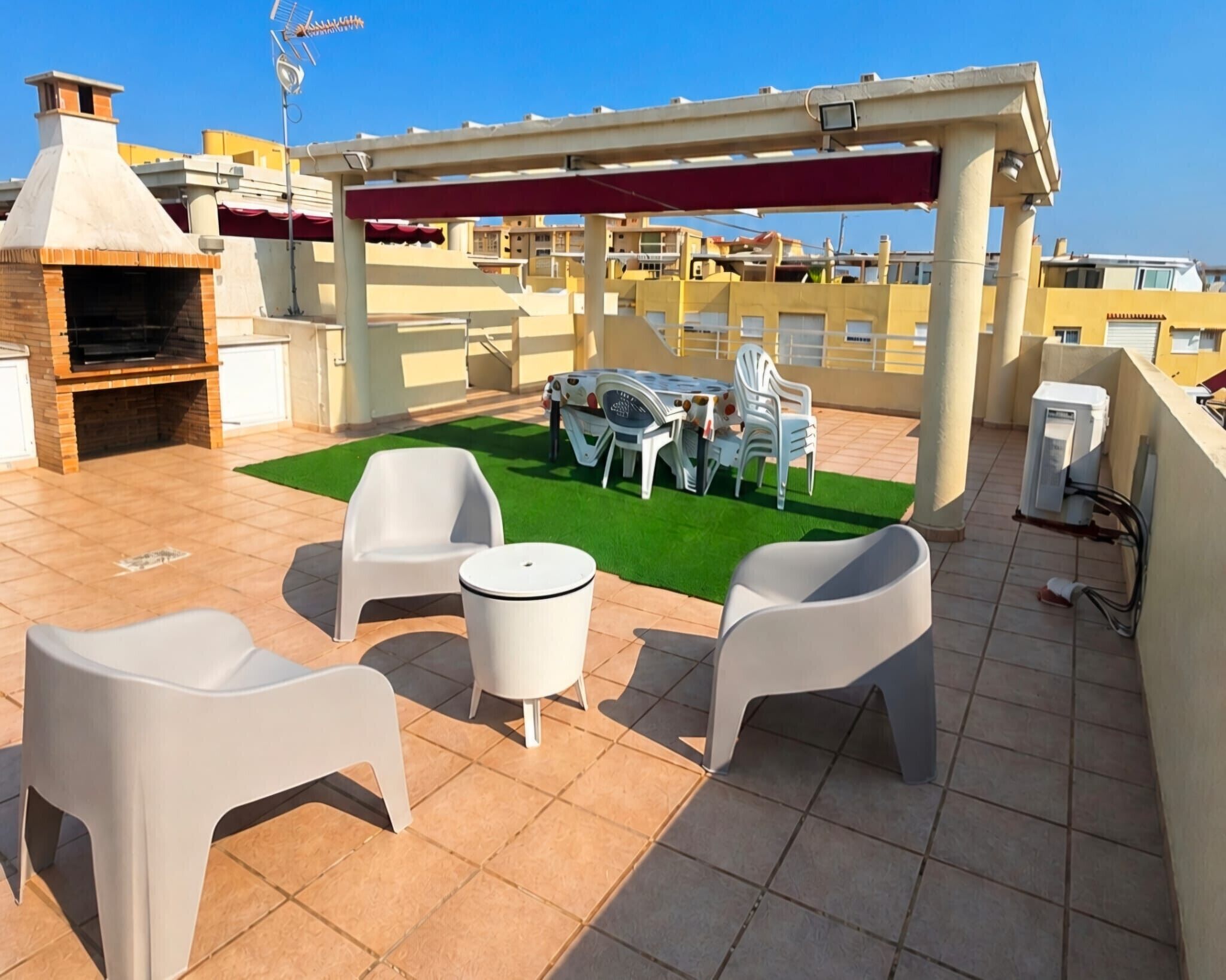 A rooftop patio with a barbecue grill, outdoor seating, and a pergola.