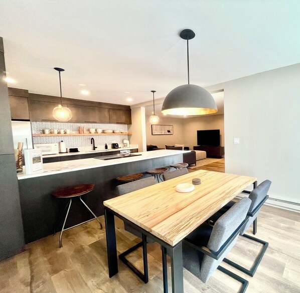 Una cocina moderna con una isla central, taburetes de bar e iluminación colgante.